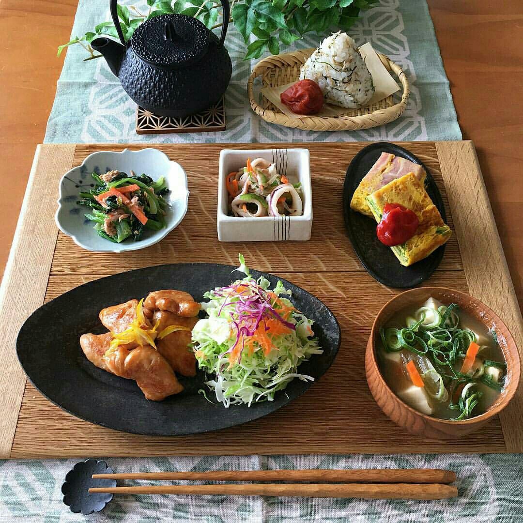急須とおにぎり、鶏肉や野菜のおかずを並べた食卓